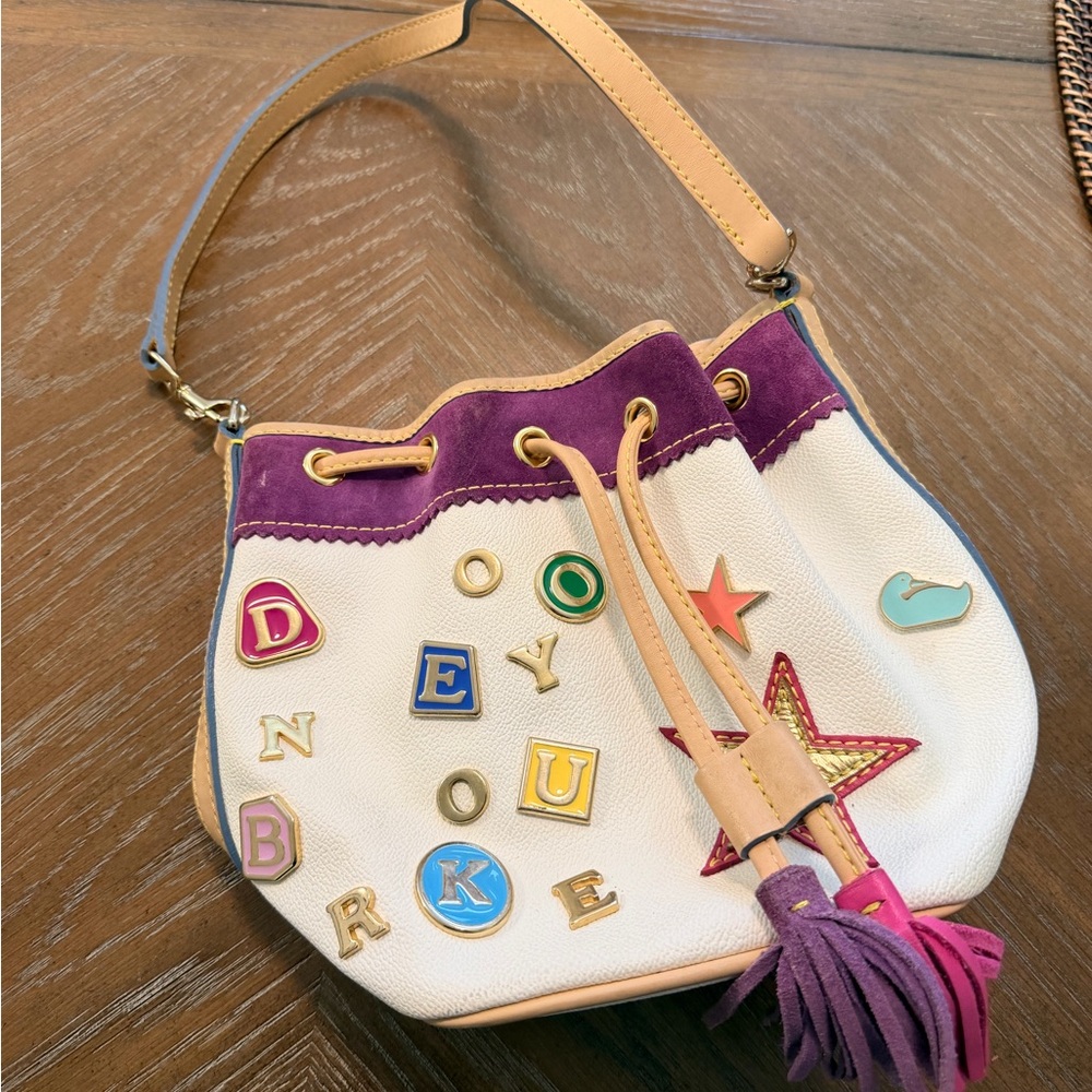 Dooney & Bourke Cream Shoulder Drawstring Bag with Purple Trim and Tan Strap